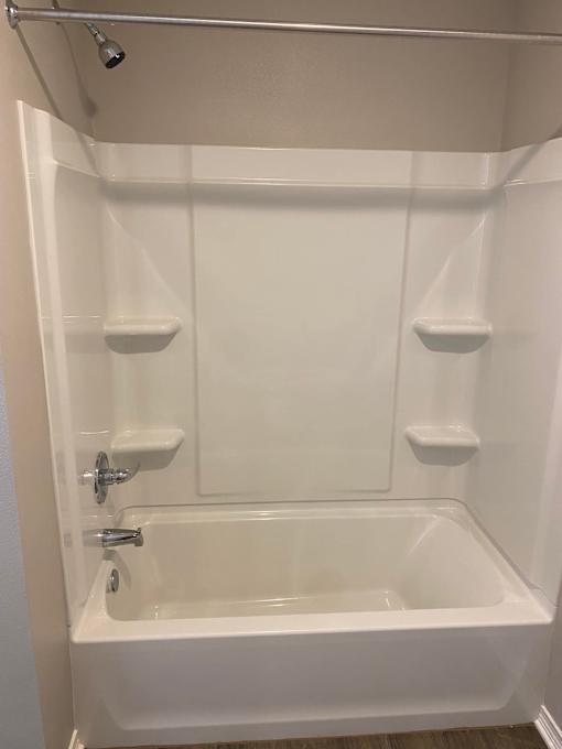 A white bathtub with a shower head above it.