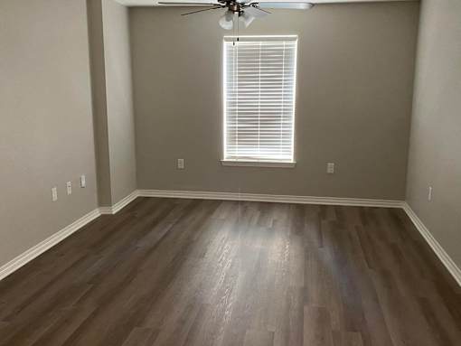 A room with a ceiling fan and a window with blinds.