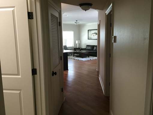 A hallway with a white door on the left and a black door on the right.