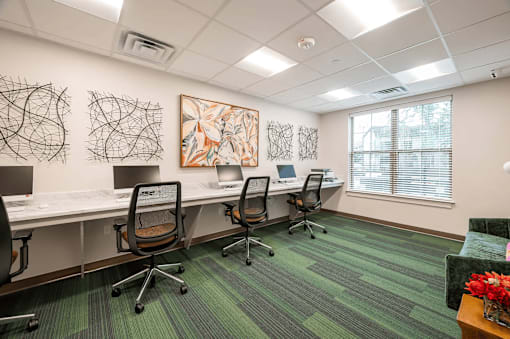 A room with a green carpet and a painting on the wall.