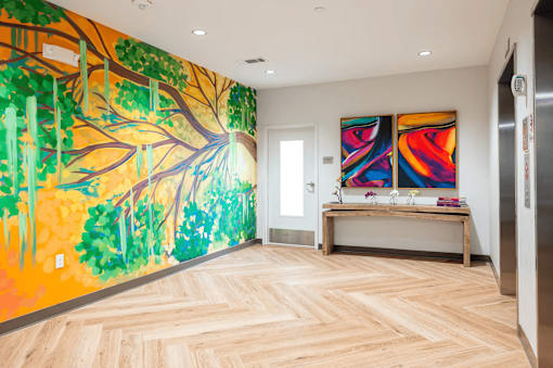 A room with a large painting of a tree on the wall.