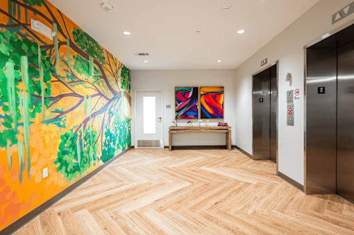 A hallway with a mural of a tree on the wall.
