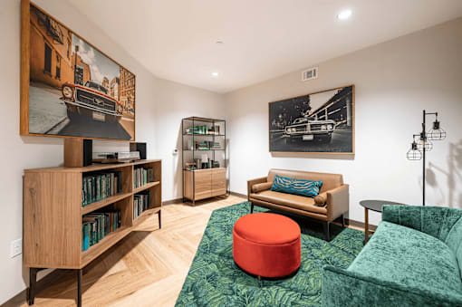 A living room with a green couch and a red ottoman.