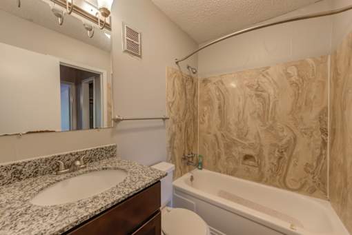 A bathroom with a marble countertop and a bathtub.