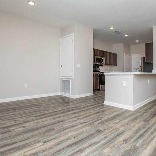 A kitchen area with a white counter and wooden flooring.