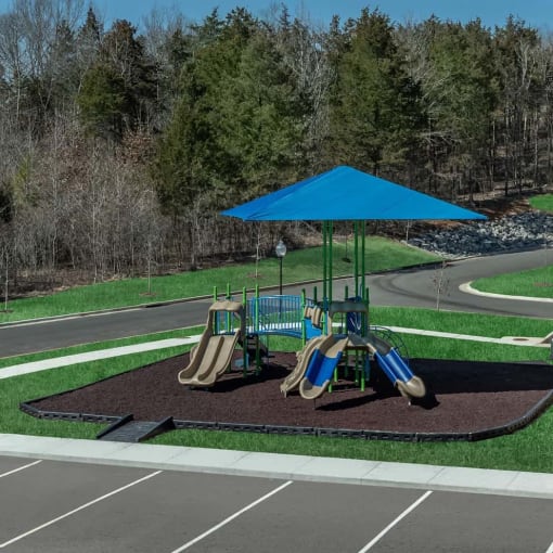 a playground with a blue umbrella and slides on it