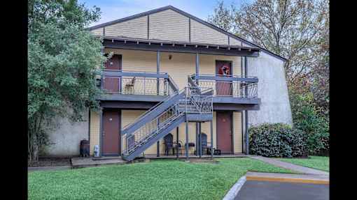 A two-story house with a red door and a balcony.