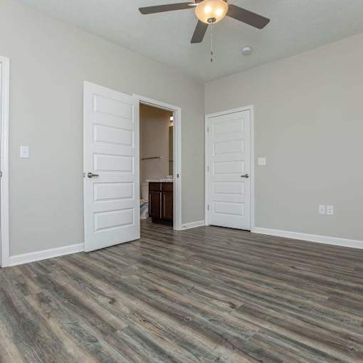 A room with a ceiling fan and wood flooring.