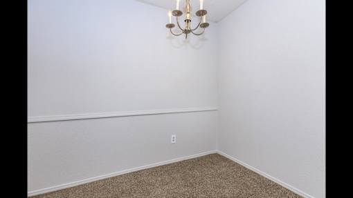 A room with a chandelier and a carpeted floor.