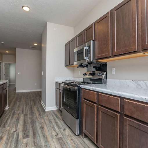 A kitchen with dark wood cabinets and a black stove top oven.