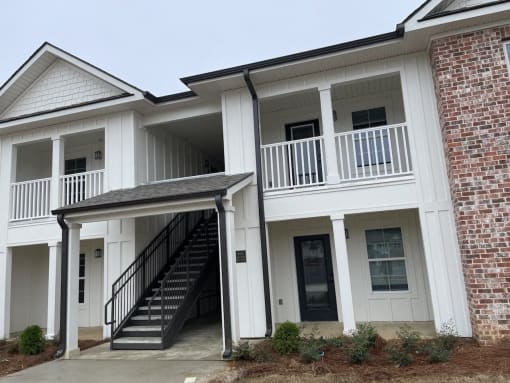 the front of an apartment building with stairs and a porch