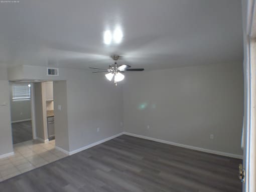 an empty living room with a ceiling fan
