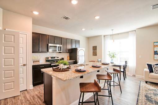 A kitchen with a large island and bar stools at Silver Oaks Apartments, Gonzales, Louisiana