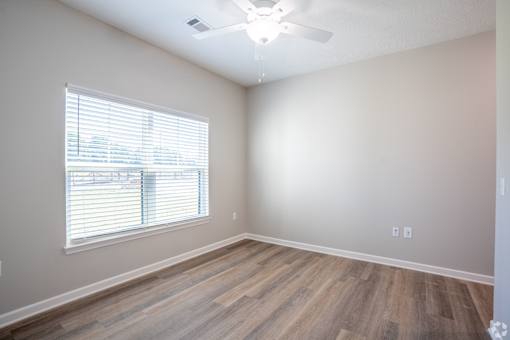 A room with a window and wooden flooring.
