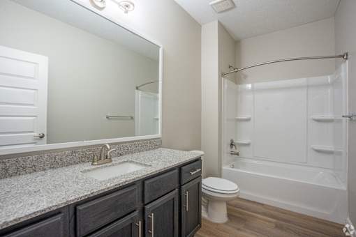 A bathroom with a white tub, sink, and toilet.