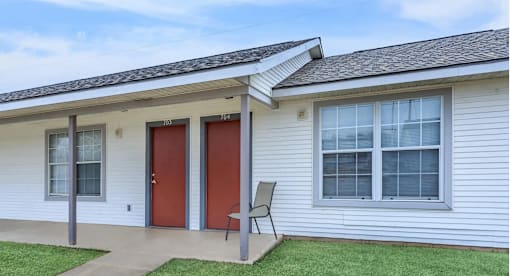 A house with a red door and a grey chair.