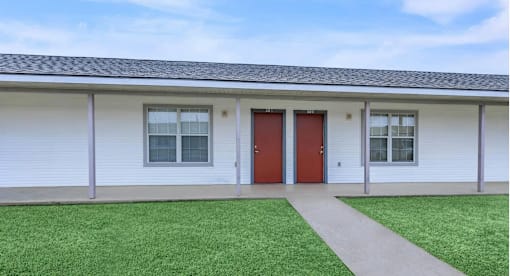 A white building with a red door and windows.