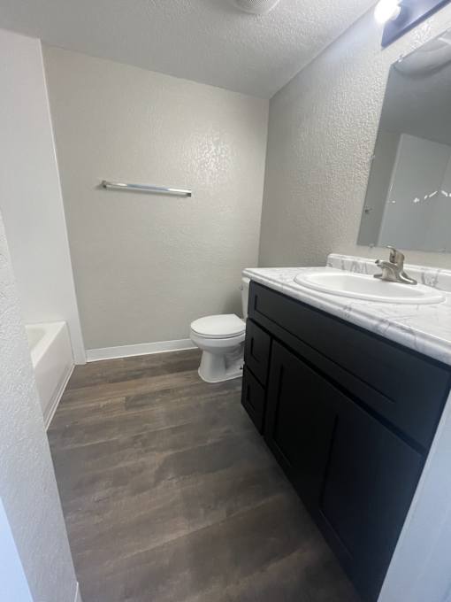 A bathroom with a toilet, sink, and a mirror.