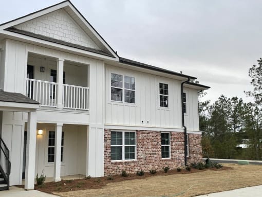 a white and brick house with a porch and a balcony