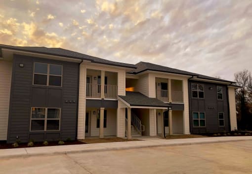 an apartment building with a parking lot and a cloudy sky