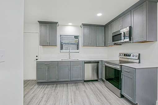 A kitchen with grey cabinets and stainless steel appliances.