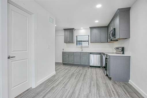A kitchen with grey cabinets and a white door.