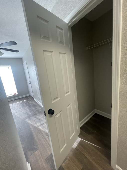 A white door is in a hallway with wood flooring.