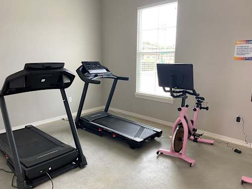 two exercise machines and a bike in a room with a window