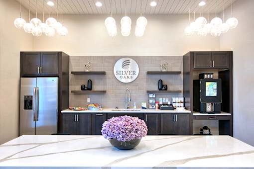A modern kitchen with a marble countertop and a vase of purple flowers in the center at Silver Oaks Apartments, Louisiana