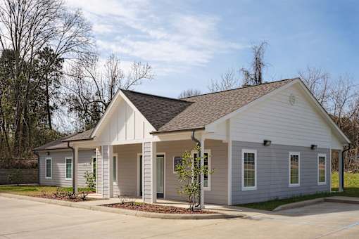 A small white house with a brown roof and a grey front porch.
