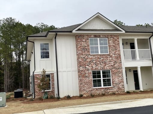 the front of a brick house with white siding and a porch