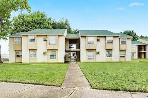 A building with a green roof and beige walls with a staircase leading to the entrance.