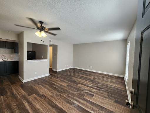 A room with a ceiling fan and wooden flooring.