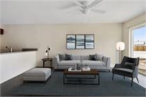 A living room with a grey couch, a black chair, and a white lamp.