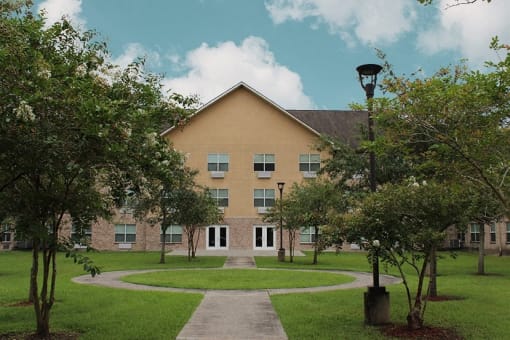 the front of a building with a lawn and trees