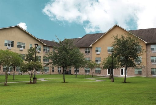 a large brick building with grass and trees in front of it