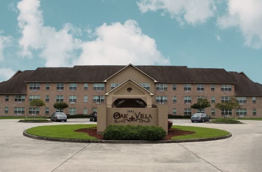 an exterior view of the oak villa building with cars parked in front of it