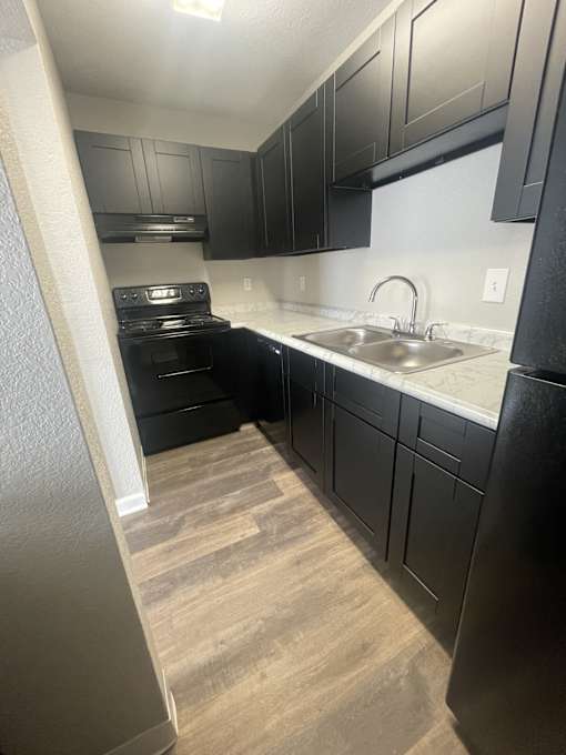 A kitchen with black cabinets and a stove top oven.
