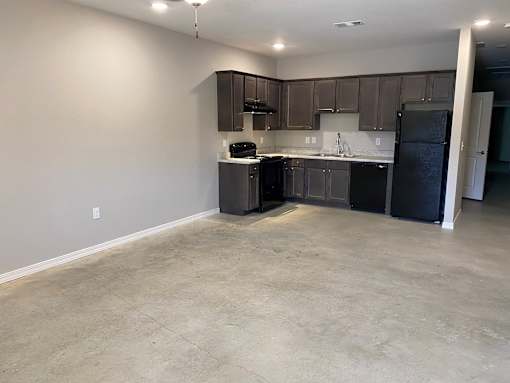 an empty kitchen with black appliances and dark cabinets