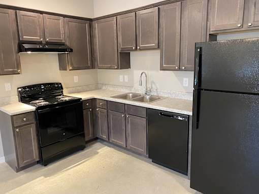 an empty kitchen with black appliances and wooden cabinets