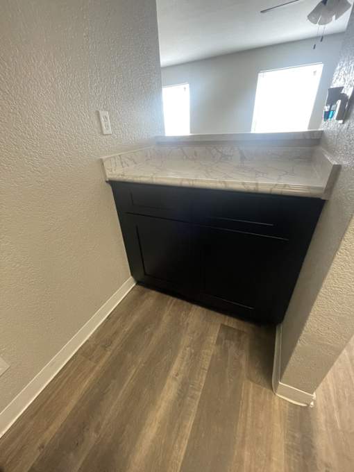 A black filing cabinet sits in a corner of a room with light wood flooring.