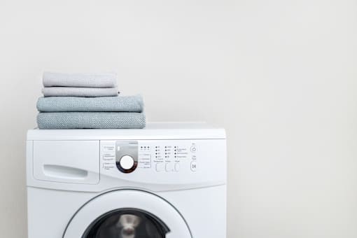 A row of white front load washing machines in a laundromat.