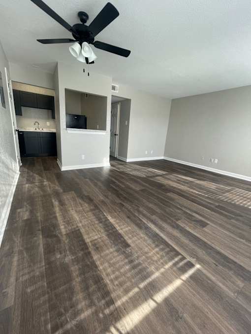 A room with a ceiling fan and wood flooring.