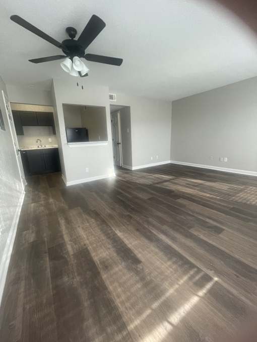 A room with a ceiling fan and wood flooring.
