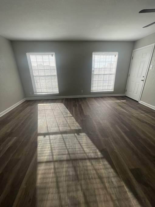 A room with wooden floors and two windows.