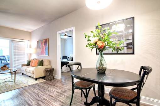 A dining room with a table set for two and a couch with pillows at Silver Oaks Apartments, Gonzales, LA 70737