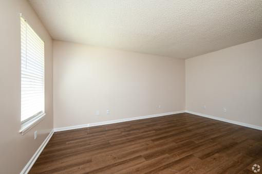 A room with wooden flooring and a window with blinds.