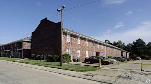 A red brick building with a parking lot in front.