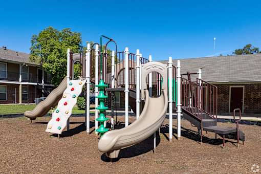 A playground with a green and white slide and a red and white slide.