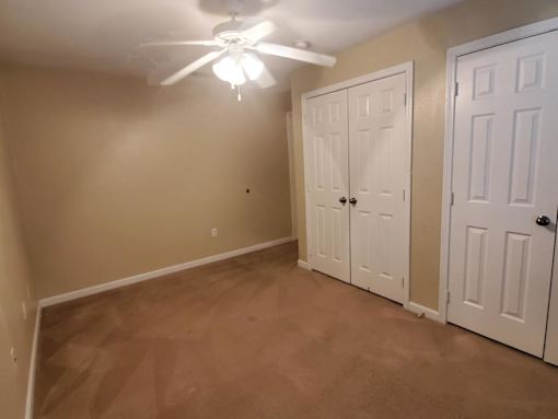 A room with a ceiling fan and two doors.